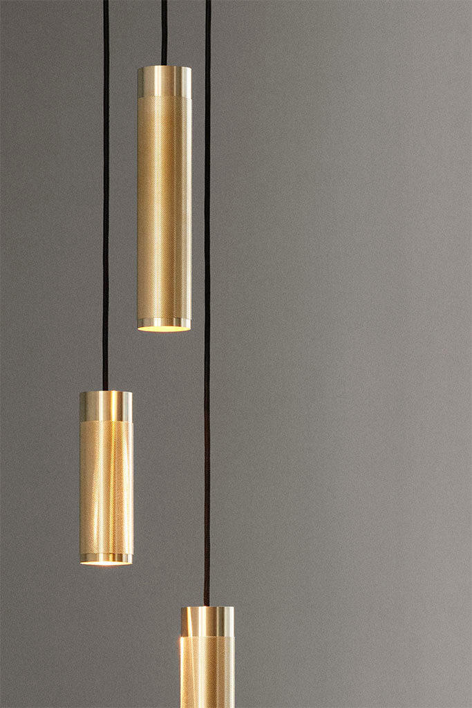 Nærbillede af loftlampe med tre pendler. Pendlerne har diamant slebet mønster og sort stofledning. Lyset er afdæmpet