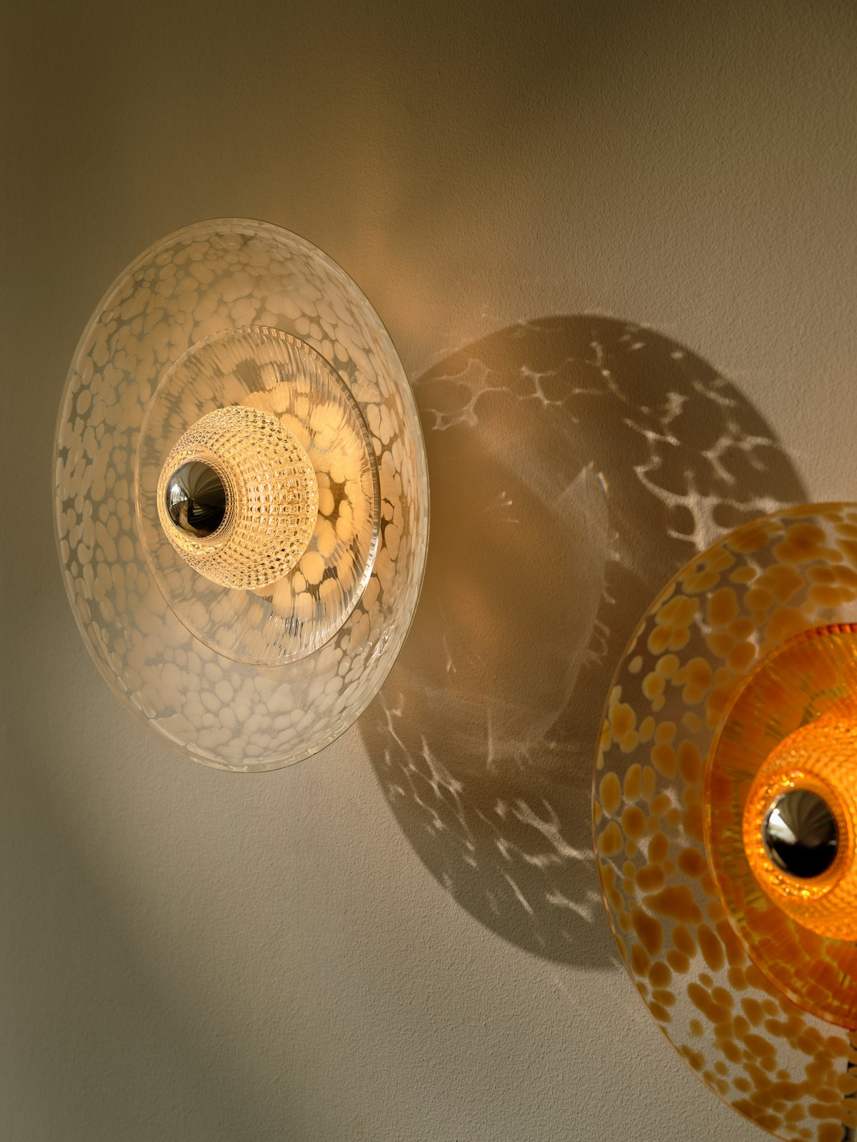 Tændt klar Disco Rama-væglampe med mønstret skygge på væggen ved en gul lampe