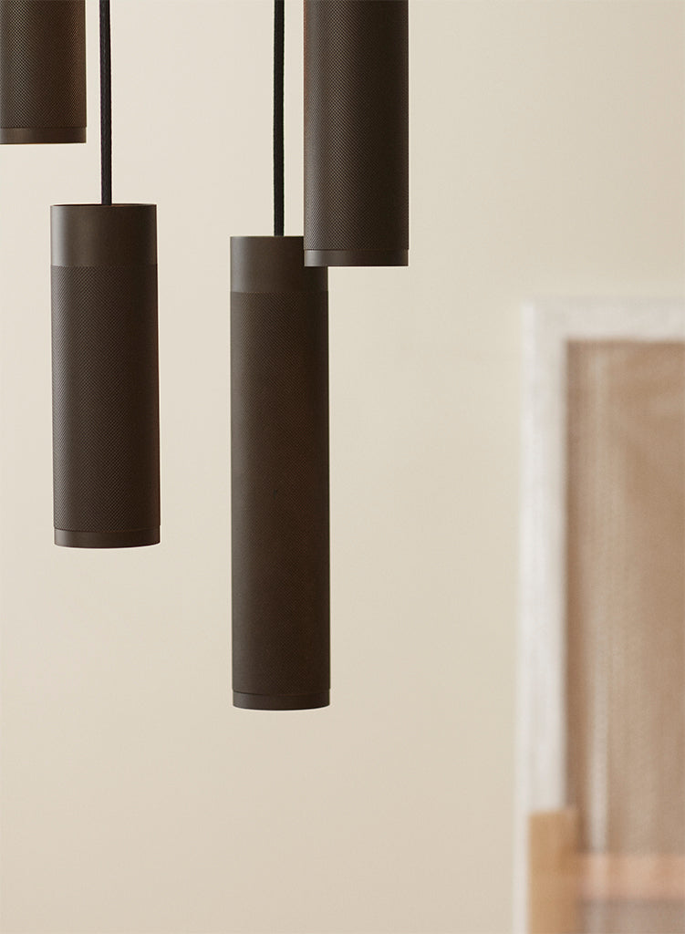 Nærbillede af loftlampe med fem pendler i massiv bruneret messing, diamant slebet mønster og sorte stof ledninger.