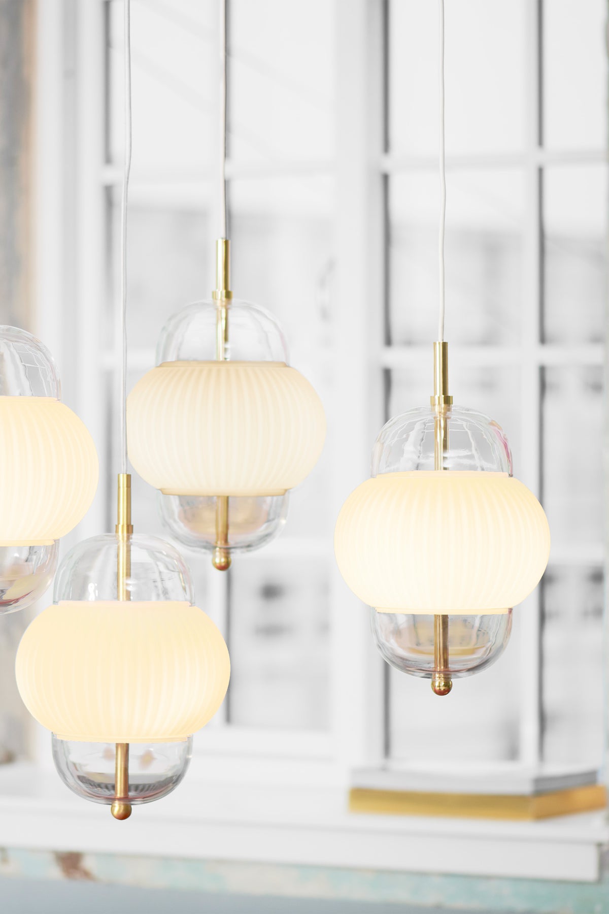 Lampe i klart glas og mat hvidt plisseret glas. Derudover har lampen detaljer i messing og en hvid stofledning. 